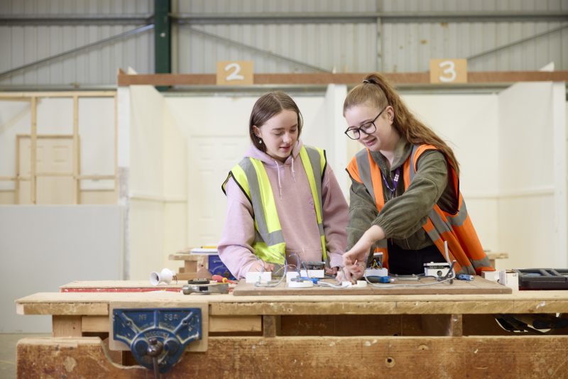 Electrical tutor showing electrical student how to wire a socket