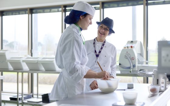 Professional bakery student mixing with lecturer supervision