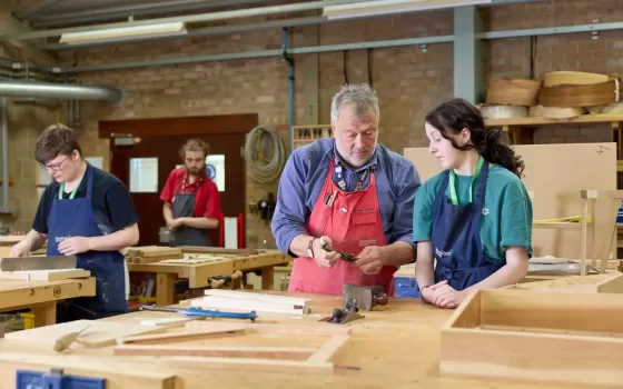 Student and lecturer looking at furniture making tools