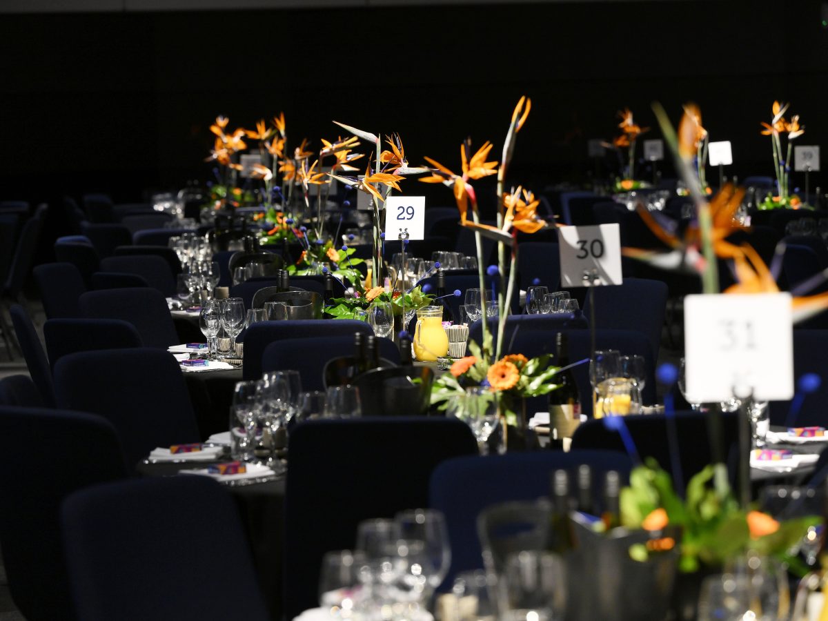 A row of floral displays on tables at the AoC Gala dinner