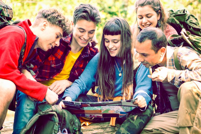 Group of five looking at map in woods